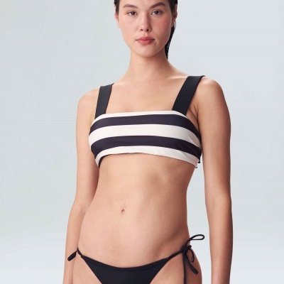Modelo usa biquíni riscas preto e branco, fundo cinzento claro