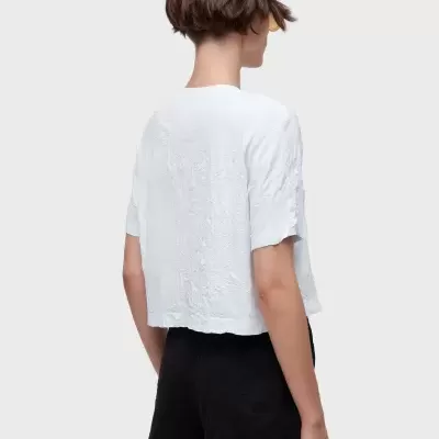 Mulher de costas com t-shirt branca de manga curta e calções pretos.