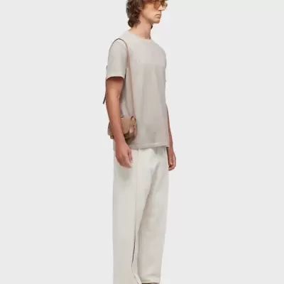 Homem com roupa casual bege e branca em fundo branco