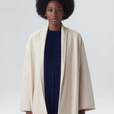 Casaco bege claro aberto com vestido azul escuro em fundo branco