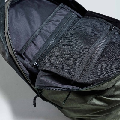 Mochila verde oliva aberta mostrando compartimentos interiores com fechos