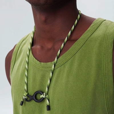 Colar com cordão verde e preto e fecho preto em forma de C numa pessoa com t-shirt verde