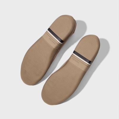 Solas de calçado bege com textura e faixa preta e branca