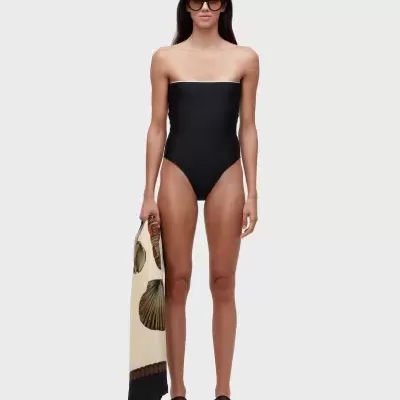 Mulher com fato de banho preto sem alças, óculos de sol e lenço com padrão de conchas