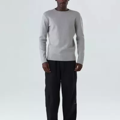 Homem com camisola cinza e calças pretas em fundo branco