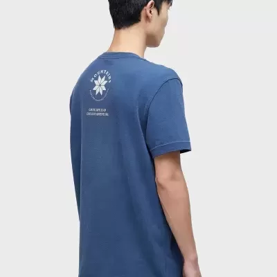 T-shirt azul de manga curta vista de costas com estampa branca e padrão de flor estilizada.