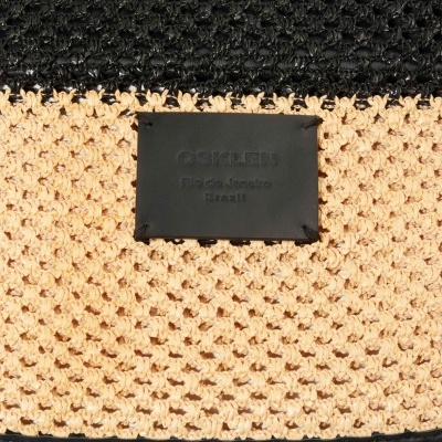 Detalhe de produto de crochê natural e branco com etiqueta preta OSKLEN