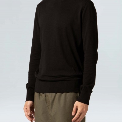 Homem vestido com camisola preta de malha e calças verdes estilo cargo