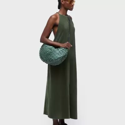 Mulher com vestido verde e mala trançada verde