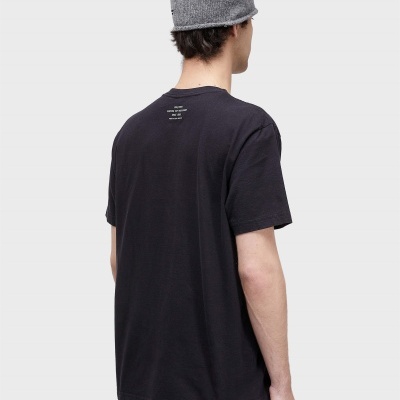 Homem de costas com camisola preta com texto branco e chapéu cinzento de malha