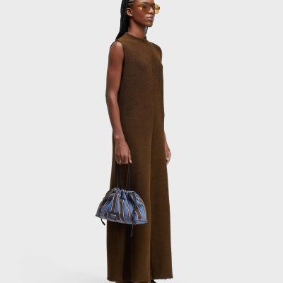 Mulher a usar vestido castanho e a segurar bolsa azul às riscas