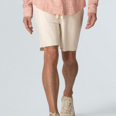 pessoa com calças curtas bege, sapatilhas bege, e camisa rosa xadrez