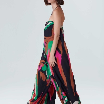 Mulher de vestido longo colorido com padrões abstratos e chapéu de palha