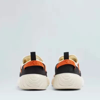 Sapatilhas desportivas pretas com detalhes laranja e sola bege vistas de trás