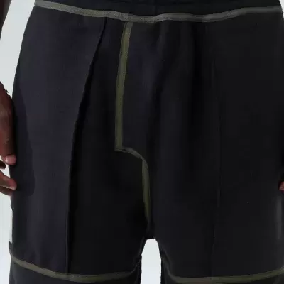 Calças pretas com costuras verdes e bolso lateral