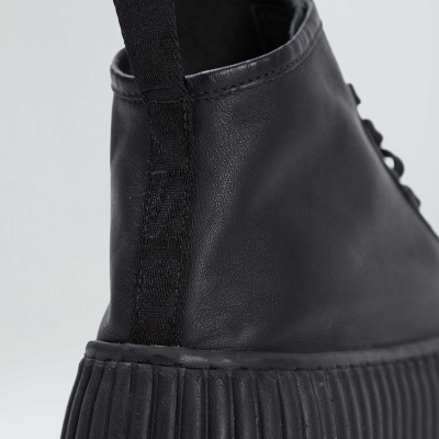 Sapatilha preta de couro com sola grossa e texturizada e puxador de tecido
