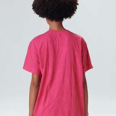 Pessoa de costas a usar t-shirt rosa de manga curta, fundo cinzento