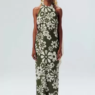 Vestido longo verde-oliva com flores brancas, lenço estampado na cabeça e sandálias claras