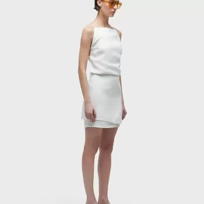 Mulher com vestido branco curto e óculos de sol âmbar