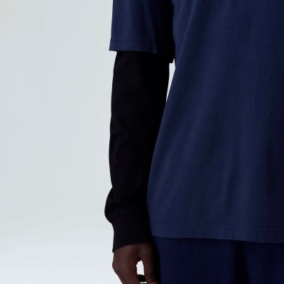 Conjunto de camisa azul de manga curta sobre camisa preta de manga longa e calças azuis.