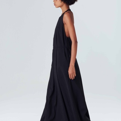 Vestido comprido preto feminino com sapatilhas brancas em fundo cinza claro