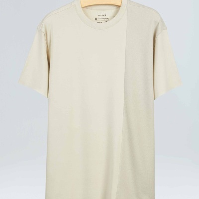 T-shirt creme com corte assimétrico pendurada em cabide de madeira