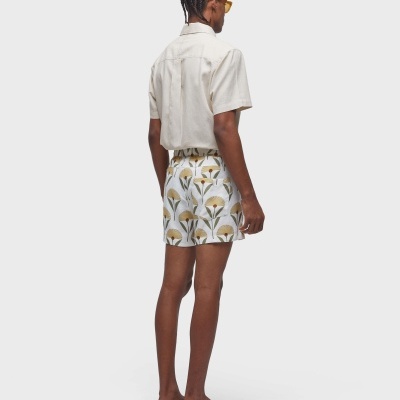 Homem de costas a usar camisa branca e calções com padrões florais amarelos e verdes