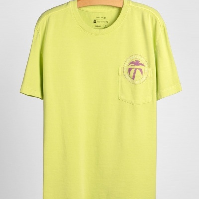 T-shirt amarela clara com bolso e estampa de palmeira lilás pendurada em cabide de madeira