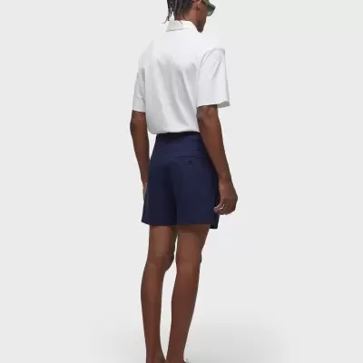 Homem de costas com camisa branca e calções azul-escuro em fundo branco