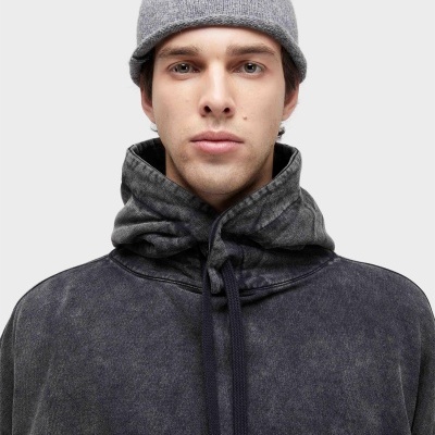 Homem com gorro cinzento tricotado e casaco cinza escuro com capuz.