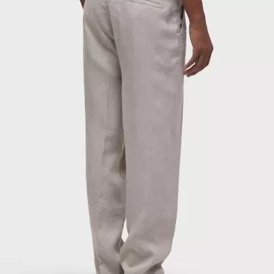 Calças cinza claro largas com bolsos traseiros, usadas com sapatos marrons e t-shirt branca