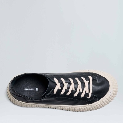 Ténis preto em pele com atacadores brancos e sola branca em fundo branco.