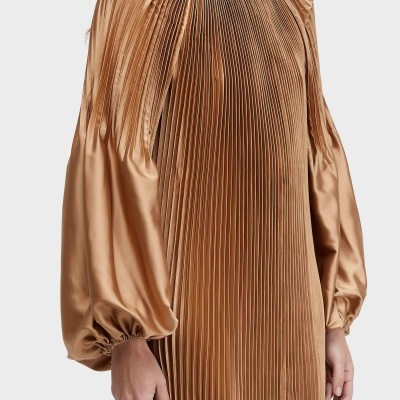 Vestido plissado cor de bronze com mangas bufantes.