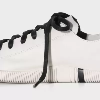 Ténis branco com atacadores pretos e sola estriada detalhe preto