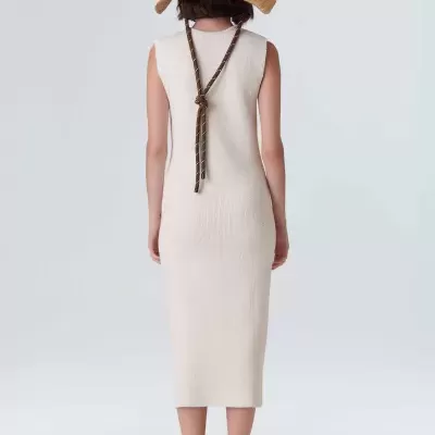 Mulher de costas com vestido branco de malha, chapéu de palha e sapatos claros