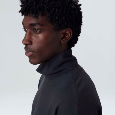 Homem de perfil com casaco preto de gola alta e cabelo encaracolado