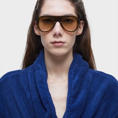 Óculos de sol castanhos com lentes degradê, modelo avaliado por pessoa com roupão azul