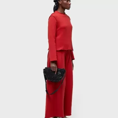 Conjunto roupa feminino vermelho com acessórios pretos contra fundo branco.