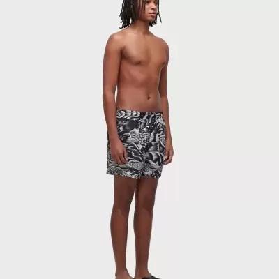 Homem com calções de banho pretos e brancos e sandálias pretas