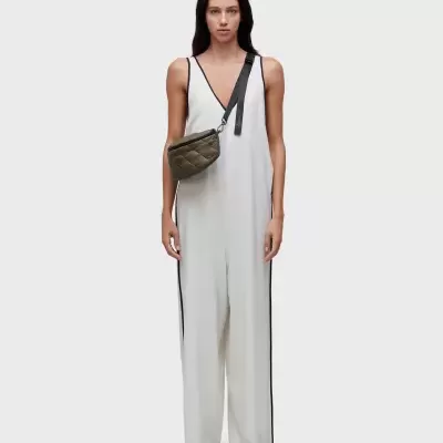 Mulher com macacão branco e bolsa tiracolo verde-oliva