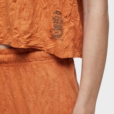Roupa laranja texturizada com calças e blusa curta com texto impresso