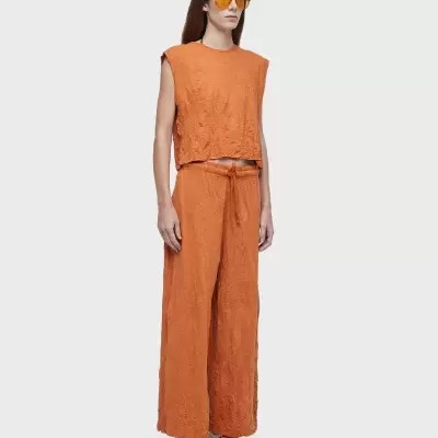 Mulher com conjunto laranja texturizado, ténis brancos e óculos amarelos