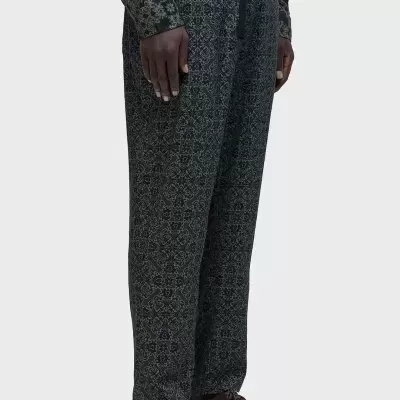 Calças cinza com padrão floral e cordão na cintura em fundo cinza.