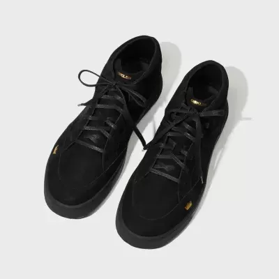 Tênis pretos de cano alto com detalhes amarelos sobre fundo branco