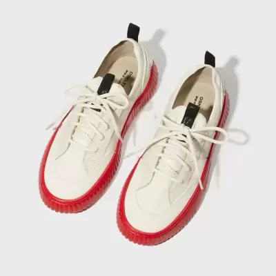 Ténis brancos com sola vermelha texturizada e detalhes em preto em fundo branco