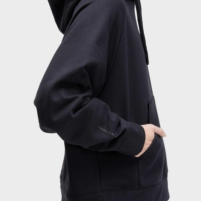 Homem vestindo sweatshirt preta com capuz e bolso canguru, detalhe do logo OSKLEN na manga.