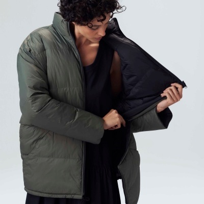 Casaco acolchoado verde-oliva com forro preto aberto em fundo cinzento