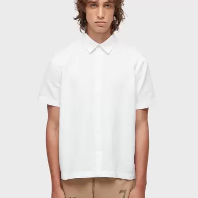 Homem com camisa branca de manga curta em fundo cinza