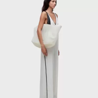 Mulher com vestido branco comprido e mala branca