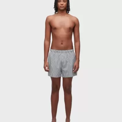 Homem com calções de banho riscado a pé em fundo branco